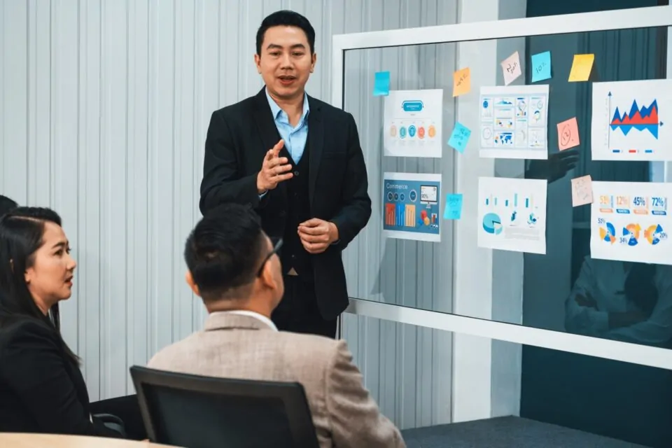 Businessman Presenting Financial Plans To Board In Meeting Room. Intellectual.